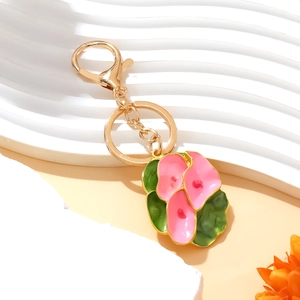 Pink enamel flower keychain with gold alloy lobster clasp on a white wavy display