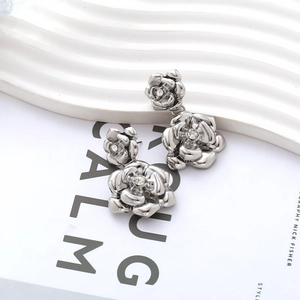 Détail macro de boucles d'oreilles camélia double couche argentées avec cristaux