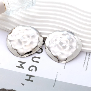 Macro shot of silver irregular hammered metal earrings with a rippled mirror finish