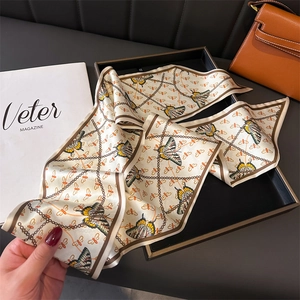 Elegant butterfly and chain print twilly scarf in cream silk, styled with fashion bag
