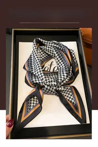 Detail of silk-like scarf with houndstooth pattern and orange accents in gift box