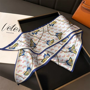 Detail of silk twilly scarf with colorful butterfly patterns and gold chain texture