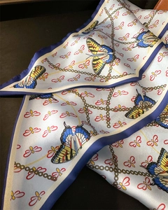Close-up of faux silk scarf showing vibrant butterfly prints and smooth satin texture