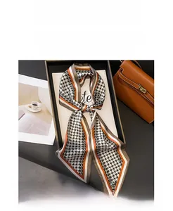 Detail of houndstooth silk scarf tied on a brown handbag for elegant styling