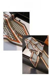 Detail of silk-like neckerchief with houndstooth and H-letter patterns in orange and brown