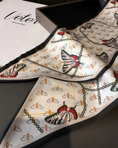Detail of silk-like scarf featuring red butterfly patterns and gold chain designs
