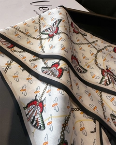 Close-up of butterfly and chain pattern on a luxurious satin silk neck scarf