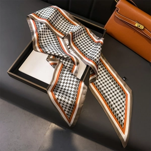 Houndstooth silk scarf with H pattern and orange accents displayed in leather tray
