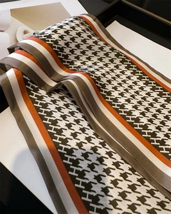 Close-up of houndstooth silk scarf featuring orange stripes and H-pattern detail