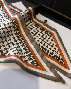 Close-up of houndstooth silk scarf with H pattern and bright orange border