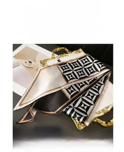 Detail of a geometric silk scarf with black, white, and brown patterns in a luxury tray