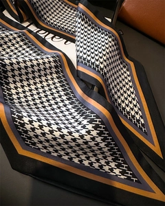 Detailed shot of houndstooth silk scarf with H patterns and elegant draped texture