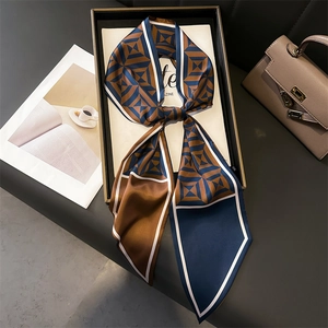 Navy and caramel geometric silk scarf tied in a gift box with a luxury leather background