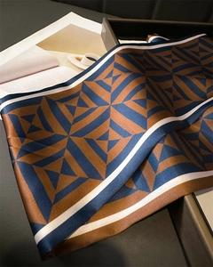 Detail of geometric silk scarf in caramel and navy with elegant draped texture