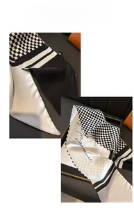 Detail of black and white checkered silk scarf with elegant cursive script lettering