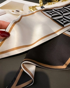 Detail of geometric color-block silk scarf with satin finish and golden-brown edges