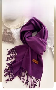 Detail of purple knitted scarf with tassels and leather label for winter warmth