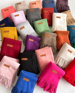 Flat lay of colorful solid scarves featuring neat fringe edges and leather logo labels