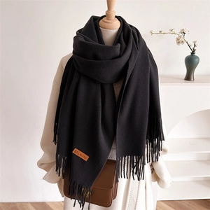 Solid black tassel scarf with brand leather label on a mannequin for autumn winter