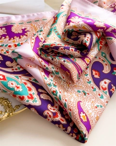 Detailed close-up showing glossy paisley silk scarf texture with vibrant purple and blue patterns