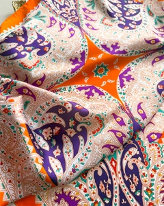 Macro shot of paisley pattern on orange and purple silk scarf showing fabric texture