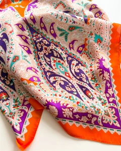 Detail of silk-like square scarf with vibrant orange border and purple paisley print