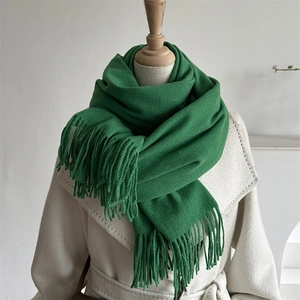 Detail of grass green knitted scarf with long fringes paired with a white fleece coat