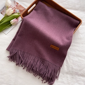 Detail of soft purple tassel scarf with premium leather brand label on fabric texture