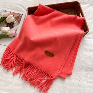 Close-up of pink tassel scarf with leather logo label in a cozy lifestyle setting