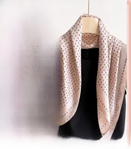 Detail of soft beige-pink paisley print silk-like scarf featuring elegant rolled edges