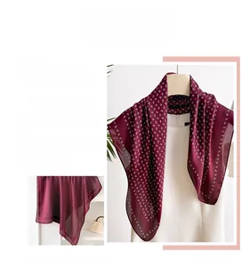Detail view of a burgundy paisley silk scarf on a mannequin showing drape and texture