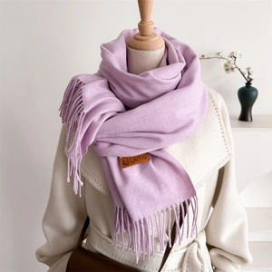 Detail of light purple soft scarf featuring a leather brand tag and delicate tassels