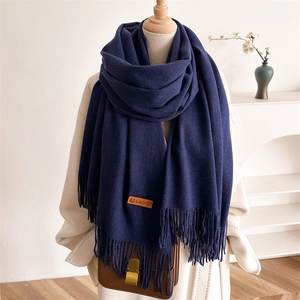Detail of dark blue scarf with fringe and brand leather patch on a wool coat