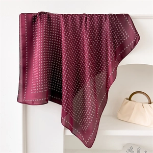 Detail of burgundy paisley satin scarf hanging elegantly showing soft silk texture