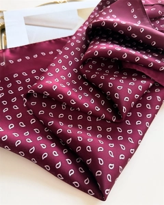 Close-up of wine red silk scarf with white paisley pattern showing smooth satin texture