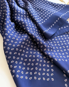 Close-up of a navy blue paisley silk scarf showing smooth texture and fine folded edges