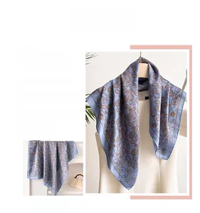 Detail eines hellblauen Seidenschals mit Paisley-Mustern und Sonnenmotiven