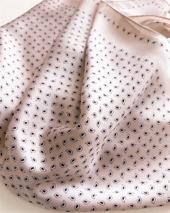 Close-up of pink satin scarf showing silk texture and black paisley pattern detail