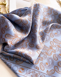 Detailaufnahme des hellblauen Seidensatinschals mit klassischen braunen Paisleymustern