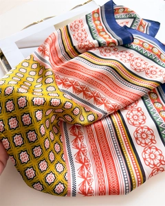 Detail of multi-color floral print silk scarf with geometric patterns and blue border
