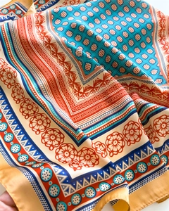 Close-up of bohemian silk scarf with floral patterns in orange and blue tones