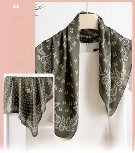 Detail of dark green paisley silk-like scarf featuring elegant white geometric patterns