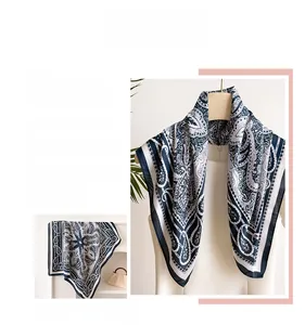 Styling detail of a navy paisley silk scarf tied around a white shirt collar