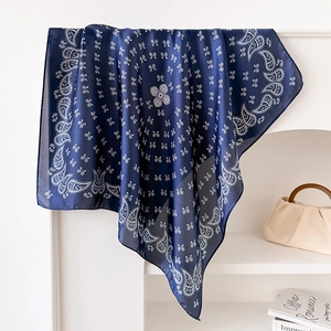 Detail of navy blue paisley print silk scarf draped elegantly on a minimalist white stand