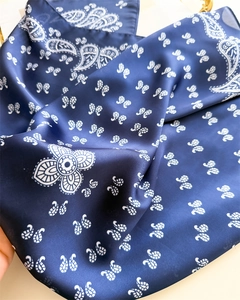 Macro view of navy blue silk scarf showing intricate white paisley print and soft texture