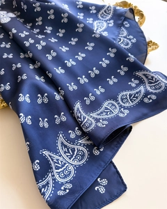 Detail of navy blue silk scarf with white paisley and butterfly prints on gold tray