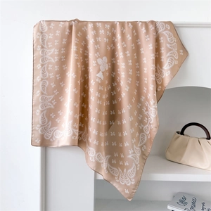 Detail of champagne paisley silk square scarf showing soft texture and elegant sheen