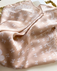 Detailed close-up of champagne paisley satin silk scarf on an elegant golden tray