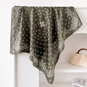 Detail of dark green silk scarf with paisley patterns draped on a minimalist rack