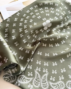 Detailed view of dark green silk-like square scarf with white paisley and butterfly prints